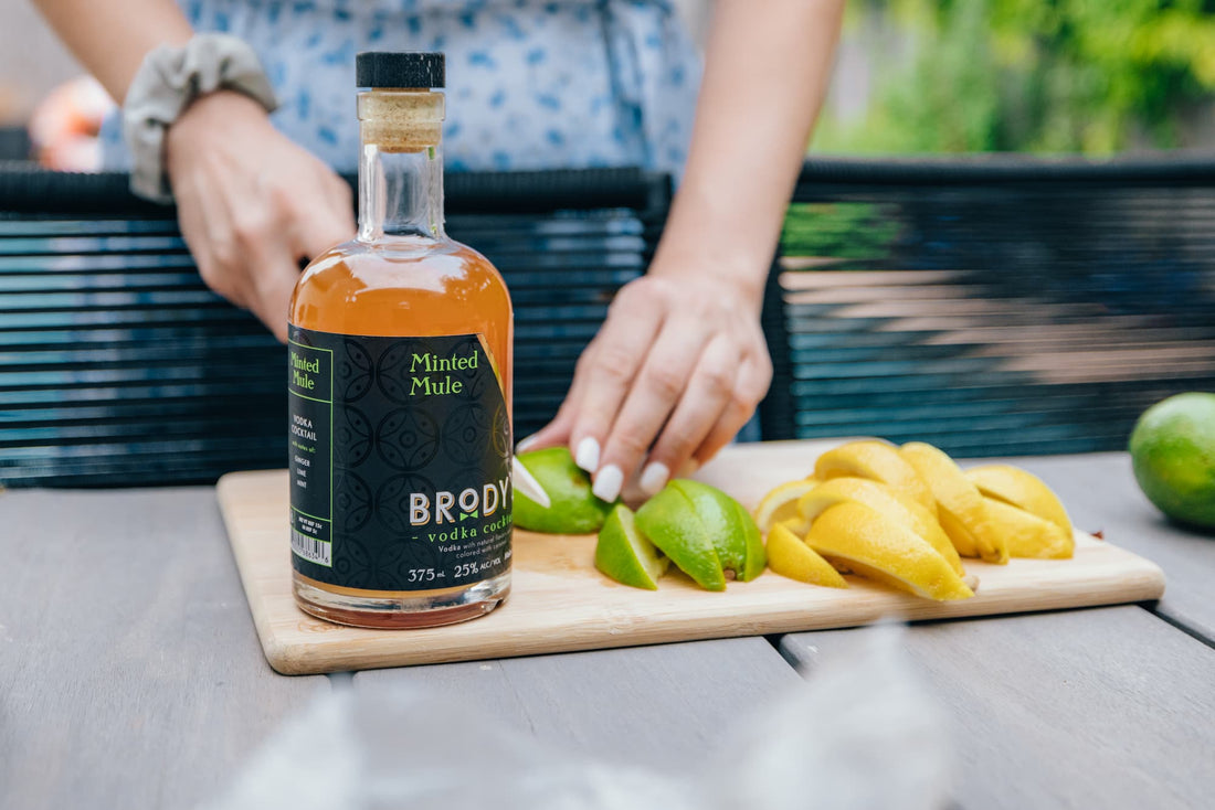 Brody's Minted Mule vodka cocktail bottle on a cutting board with fresh lime wedges, ready to serve