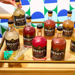 Eight Brody's crafted cocktail bottles arranged on a bar cart