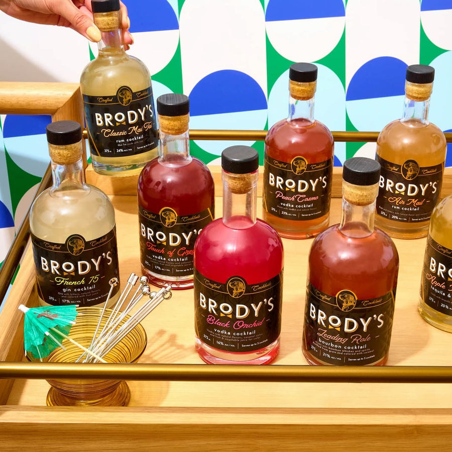 Eight Brody's crafted cocktail bottles arranged on a bar cart