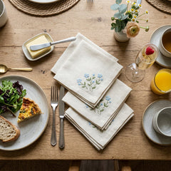 Stack of four cream and blush linen cocktail napkins with a coupe of pink cocktail and a sprig of garnish nearby — included with Brody's Boozy Brunch Bundle.