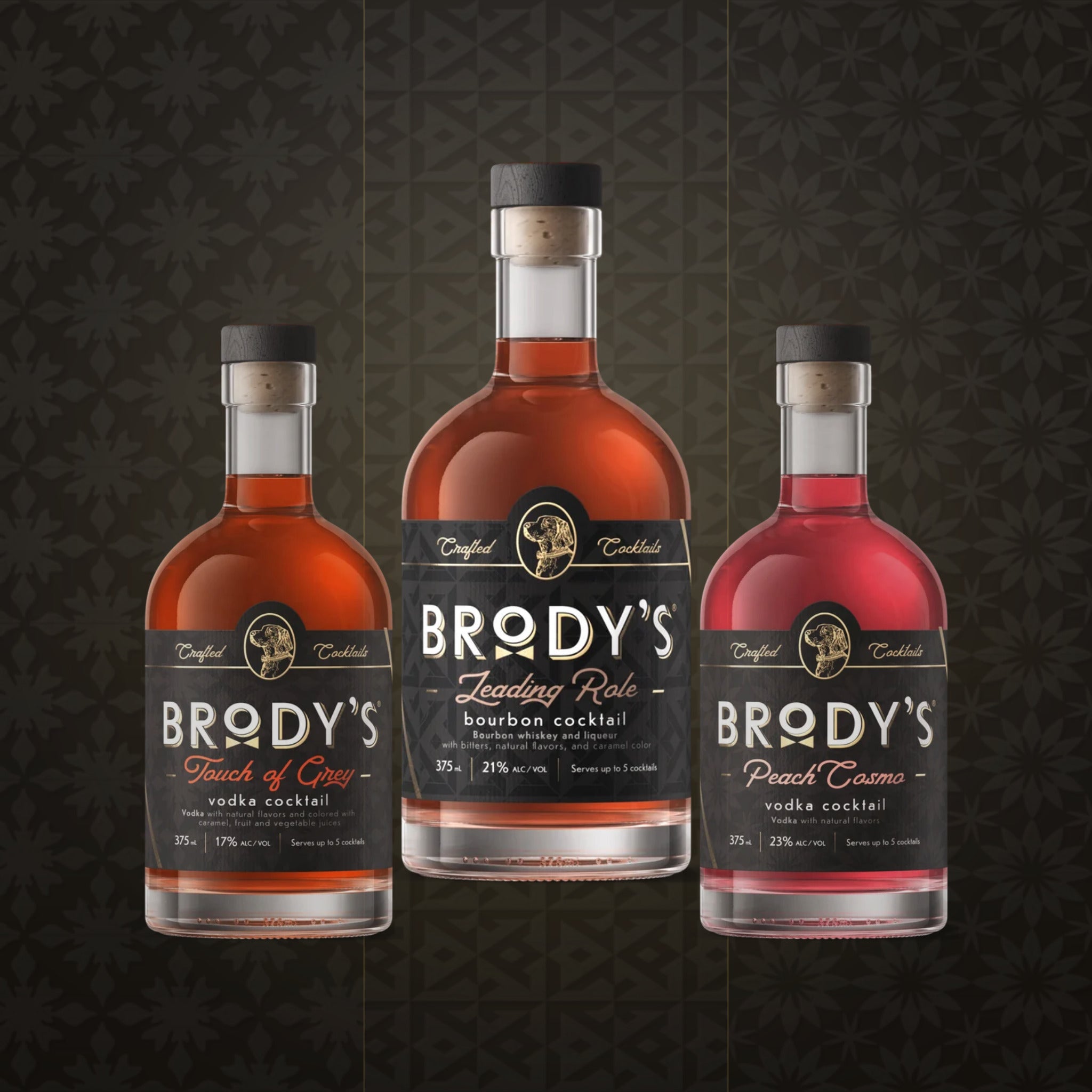 Three bottles of Brody's Cocktails. The center bottle is 'Leading Role' bourbon cocktail, flanked by 'Touch of Grey' and 'Peach Cosmo' bottles.
